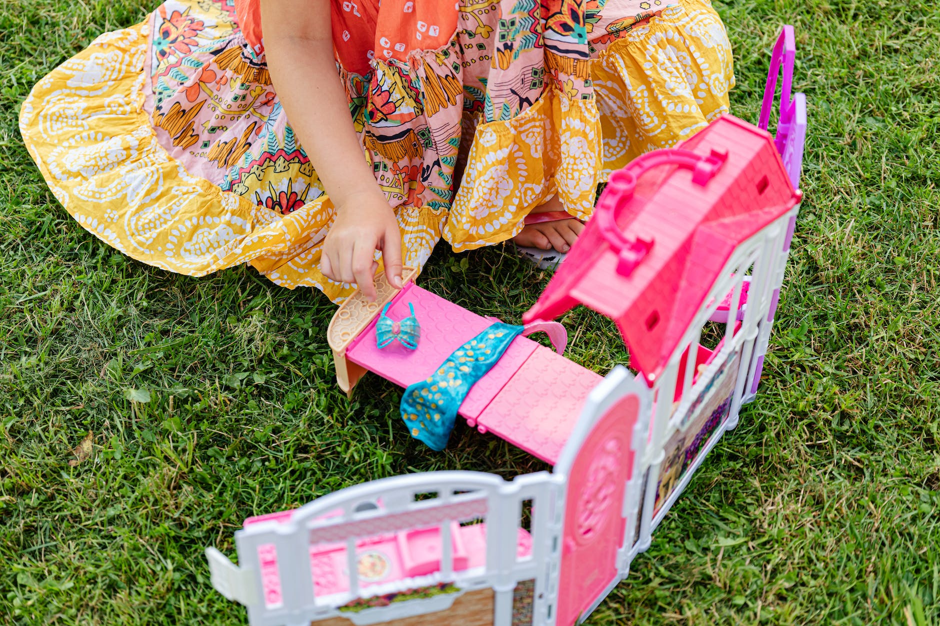 girl in floral dress playing mini bedroom toy